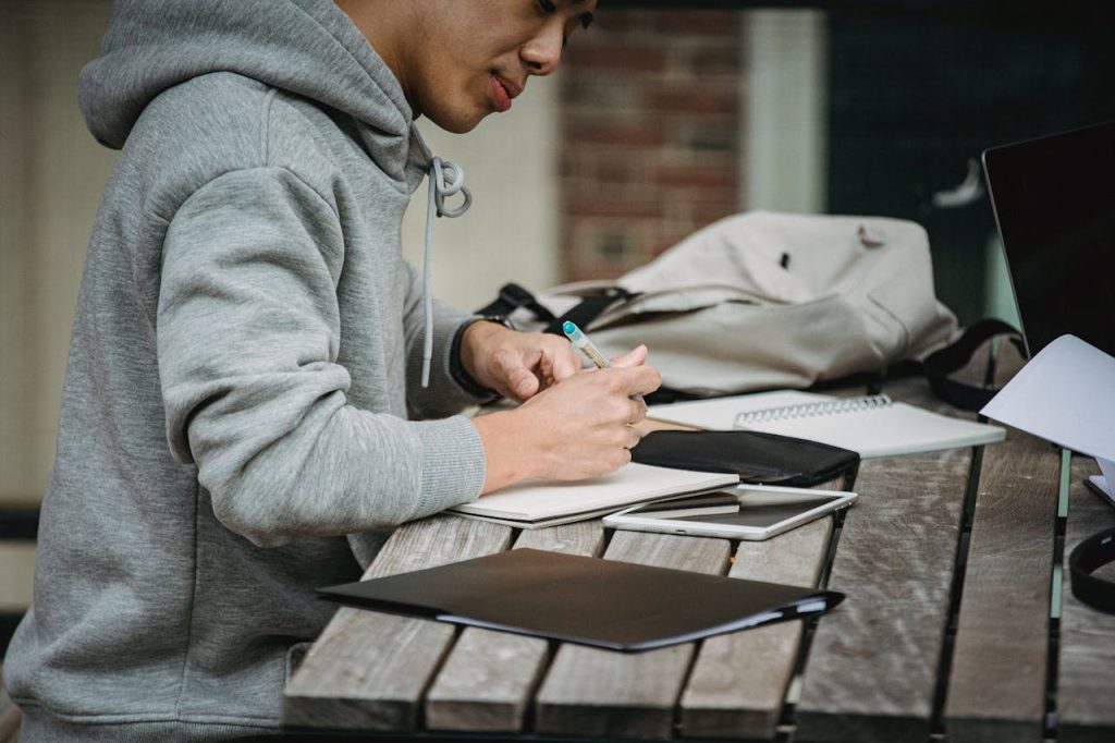 Crop man writing in notebook